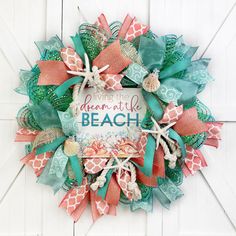 a wreath on the door that says dream at the beach with seashells and starfish