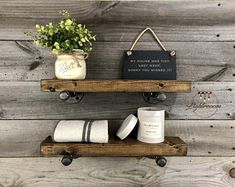 two wooden shelves with towels, candles and a potted plant on one shelf that says my house was too last week don't you missed it