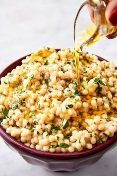 a bowl filled with macaroni and cheese being drizzled with dressing