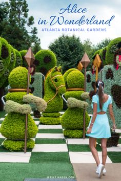 a woman in a blue dress is walking by some fake plants