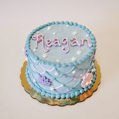 a blue cake with the word reagan on it sitting on top of a white table