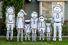 a group of people standing in front of a house with paper cutouts on them