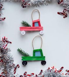 christmas decorations made out of popsicle sticks and wooden toy cars are hanging on tinsel