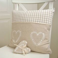 a white chair sitting next to a pillow on top of a wooden table with a bow