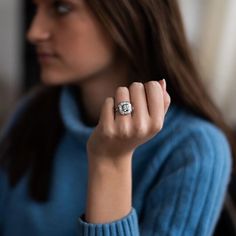 a woman wearing a blue sweater holding a diamond ring