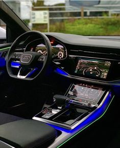 the interior of an audi car with blue lights and black leather seats, including steering wheel