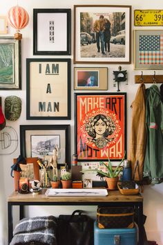 a living room filled with lots of pictures on the wall above a desk and chair