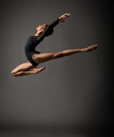 a ballerina in the air with her legs spread out and one leg bent forward