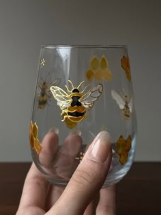 a hand holding a wine glass with bees on it