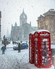 a red phone booth sitting in the middle of a snow covered street