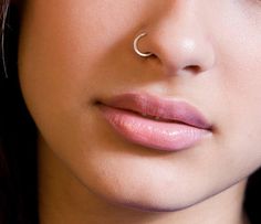 a close up of a woman with a nose ring on her nose and piercing in the middle