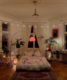 a bedroom with white walls, wooden floors and lots of plants on the windowsill