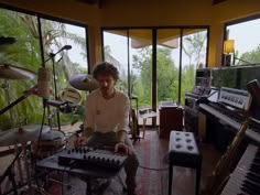 a man sitting in front of a keyboard next to a piano and other musical instruments