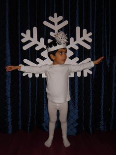 a young boy standing in front of a snowflake backdrop with his arms outstretched