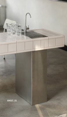 a sink and counter in a room with tile flooring on the walls, along with two chairs