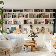 a living room filled with white furniture and lots of bookshelf above it's fireplace