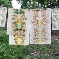 three towels are hanging on a clothes line in the grass with trees and bushes behind them