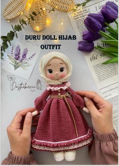 the doll is wearing a red dress and white bonnet with pink flowers in the background