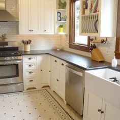 a kitchen with white cabinets and black counter tops, an oven, dishwasher and sink