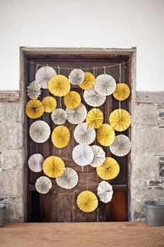 paper fans are hanging on the wall next to an old wooden door and table cloths