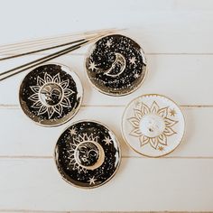 three black and white plates with gold designs on them next to chopsticks, one has a moon and the other has a crescent