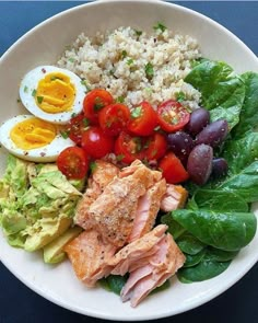 a white bowl filled with meat, vegetables and rice next to an egg on top of lettuce