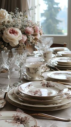 the table is set with plates, silverware and flowers in vases on it