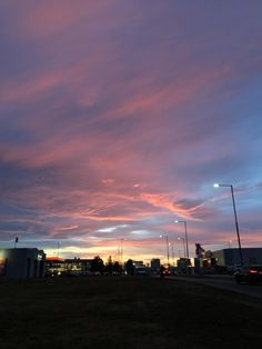 the sky is pink and blue with clouds in it at sunset or dawn, as seen from an empty parking lot