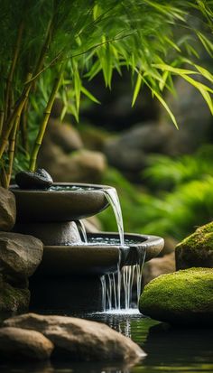 there is a small waterfall in the middle of some rocks and water with green plants around it