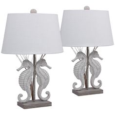 two seahorse lamps with white shades on them