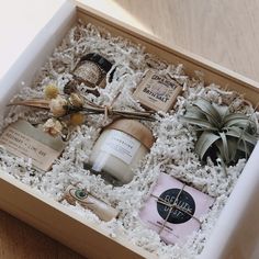 an open box filled with personal care items on top of a wooden table next to a potted plant