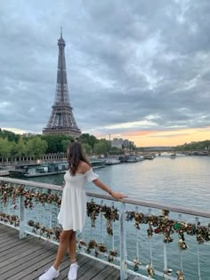 a woman is standing on a bridge overlooking the eiffel tower