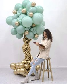 a woman sitting on a stool next to a balloon tree