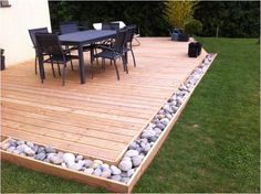 a wooden deck surrounded by rocks and chairs