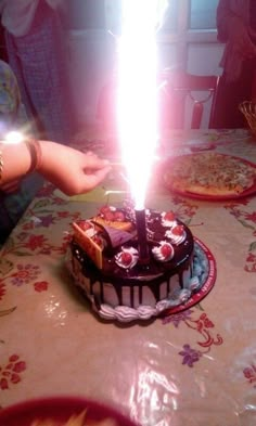 a birthday cake sitting on top of a table with a lit candle sticking out of it