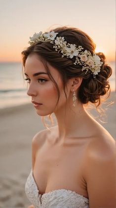 a woman in a wedding dress on the beach wearing a floral headpiece with flowers