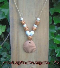 a necklace with shells is hanging on a wooden board