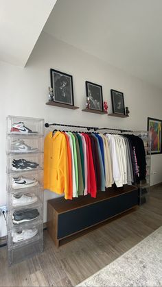 a clothing rack with shirts and shoes on it in a room filled with framed pictures