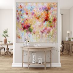 an abstract painting hangs on the wall above a table