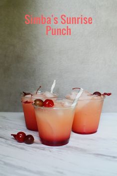 three glasses filled with drinks sitting on top of a white table next to cherries