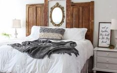 a bedroom with white bedding and wooden headboard, two nightstands and a mirror on the wall