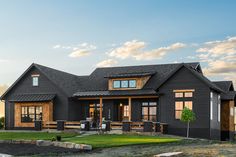 a black house with lots of windows on the front and side of it, surrounded by grass