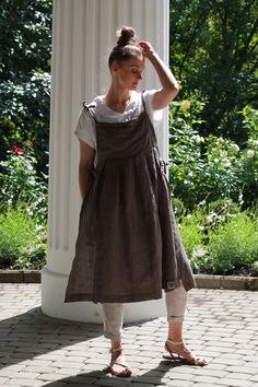 a woman standing in front of a white pillar with her hand on her head and wearing sandals