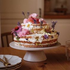 a cake sitting on top of a wooden table covered in frosting and colorful flowers