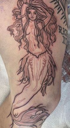 a woman with long hair sitting on top of a man's leg wearing a tattoo