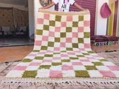 a woman standing in front of a pink and green checkered blanket on the ground