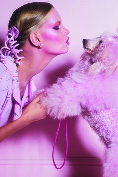 a woman is kissing her poodle while wearing pink makeup