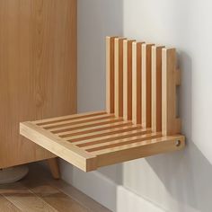 a wooden chair sitting on top of a hard wood floor next to a white wall