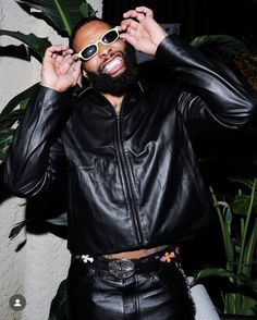 a man in black leather jacket and sunglasses posing for the camera with his hands on his head