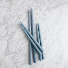 three blue candles sitting on top of a marble counter